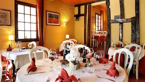 A restaurant with round tables set for dining, featuring white chairs and red napkins. - Logis Auberge de la Treille (Saint-Martin-le-Beau)