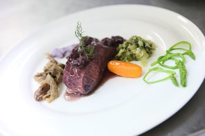 A plate with a piece of meat, a carrot, and some greens. - Logis Auberge de la Treille (Saint-Martin-le-Beau)