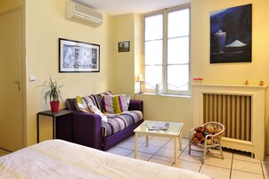 Une pièce comprenant un lit, un canapé, une chaise, une table, une fenêtre et une cheminée.