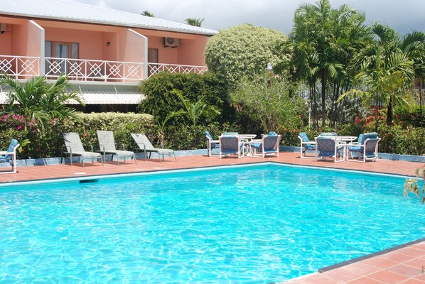 A swimming pool with lounge chairs and a building in the background.