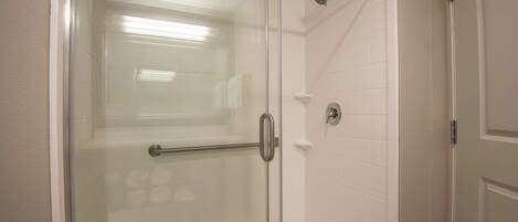 A glass-enclosed shower with a metal handle and a glass door.