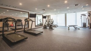 Un gimnasio con cintas de correr, elípticas y pesas libres.