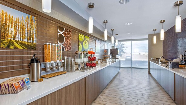 Una barra de desayuno moderna con fondo de madera, dispensadores de café y vistas al exterior.