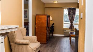 A room with a wooden dresser, a chair, a desk, and a window with curtains.