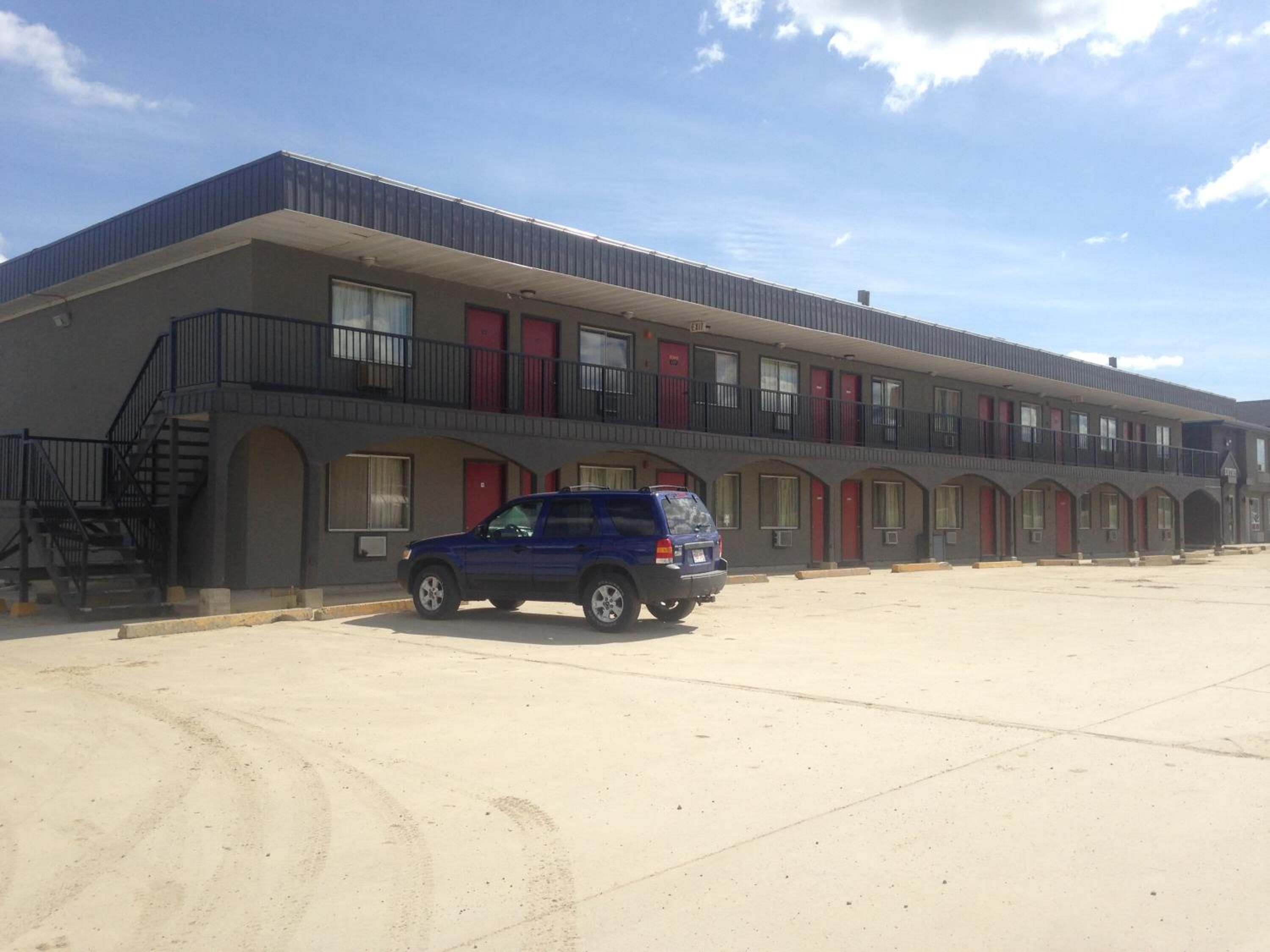 Un motel con una hilera de habitaciones, cada una con una puerta roja y un balcón.