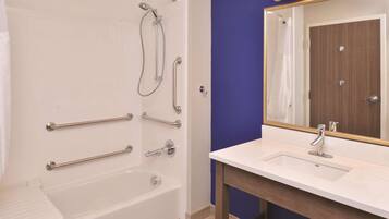 Une salle de bain avec une baignoire, une douche, un lavabo et un miroir.