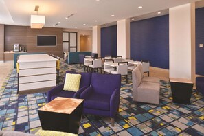 A hotel lobby with a reception desk, seating area with sofas and chairs, a large screen, and a patterned carpet. - La Quinta Inn & Suites by Wyndham Page at Lake Powell (Page)