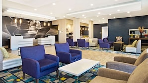 A spacious lobby with modern seating, a reception desk, and a large abstract mural on the wall. - La Quinta Inn & Suites by Wyndham Page at Lake Powell (Page)