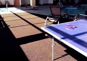 A pool area with a ping pong table, lounge chairs, and a poolside table. - Motel 6 Hastings, NE (Hastings)