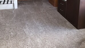 Cocina compacta con armarios de madera, microondas y una pequeña zona de estar con una silla de metal.