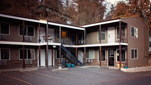 Un motel de varios pisos con una escalera central, asientos al aire libre y un estacionamiento.