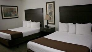 Habitación de hotel con dos camas, una mesita de noche, una lámpara y un cuadro en la pared.