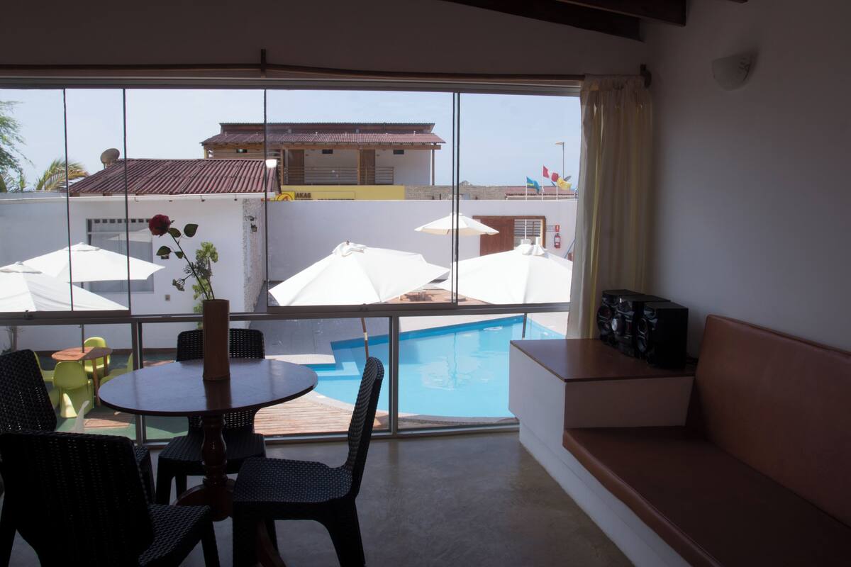 A balcony with a pool, a table with chairs, and a sofa.