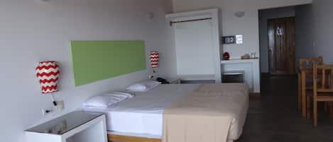 Un dormitorio con cama, mesita de noche, lámpara y pared verde.