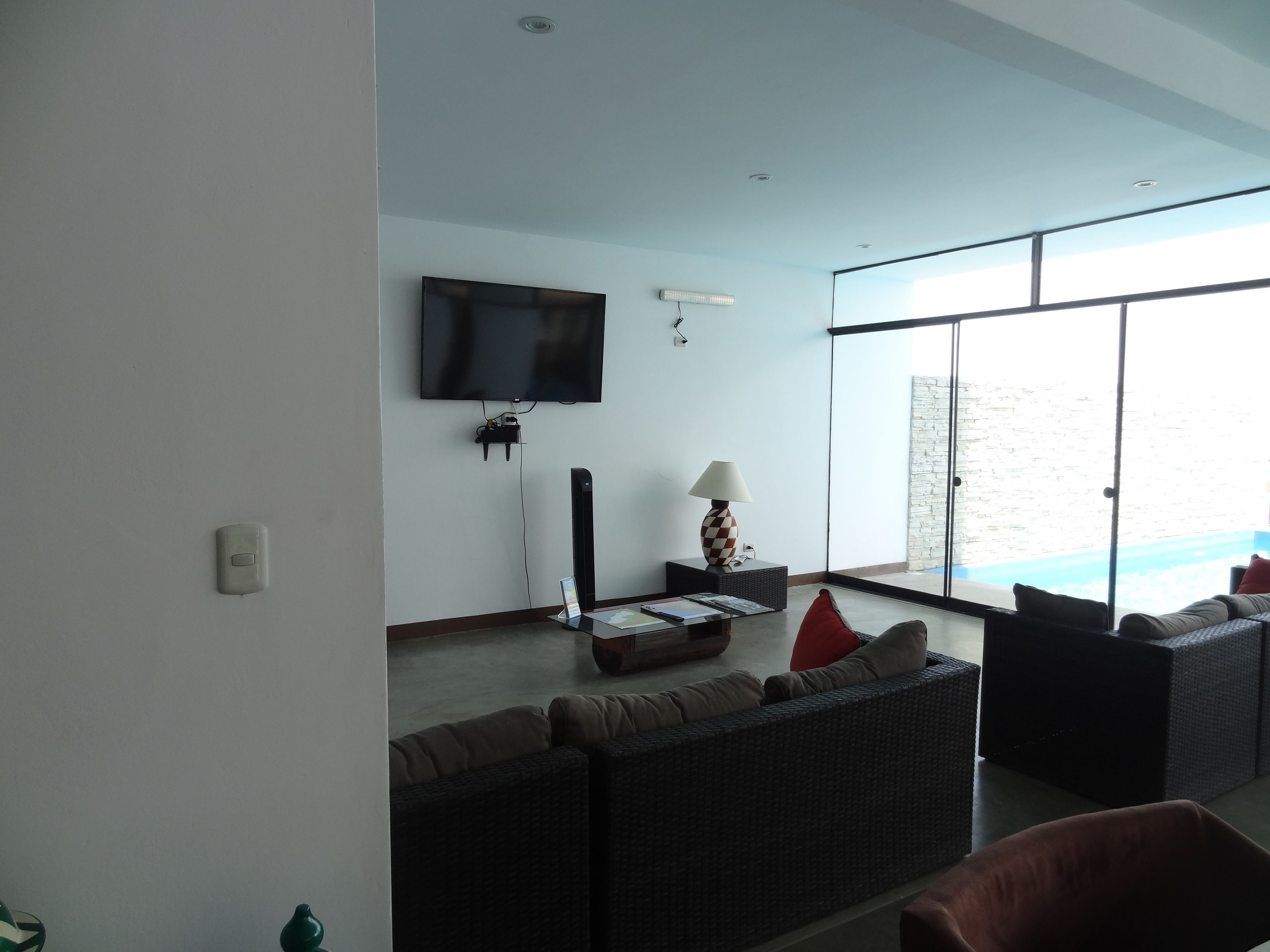 A modern living room with a flat-screen TV, a standing lamp, and a sofa set.