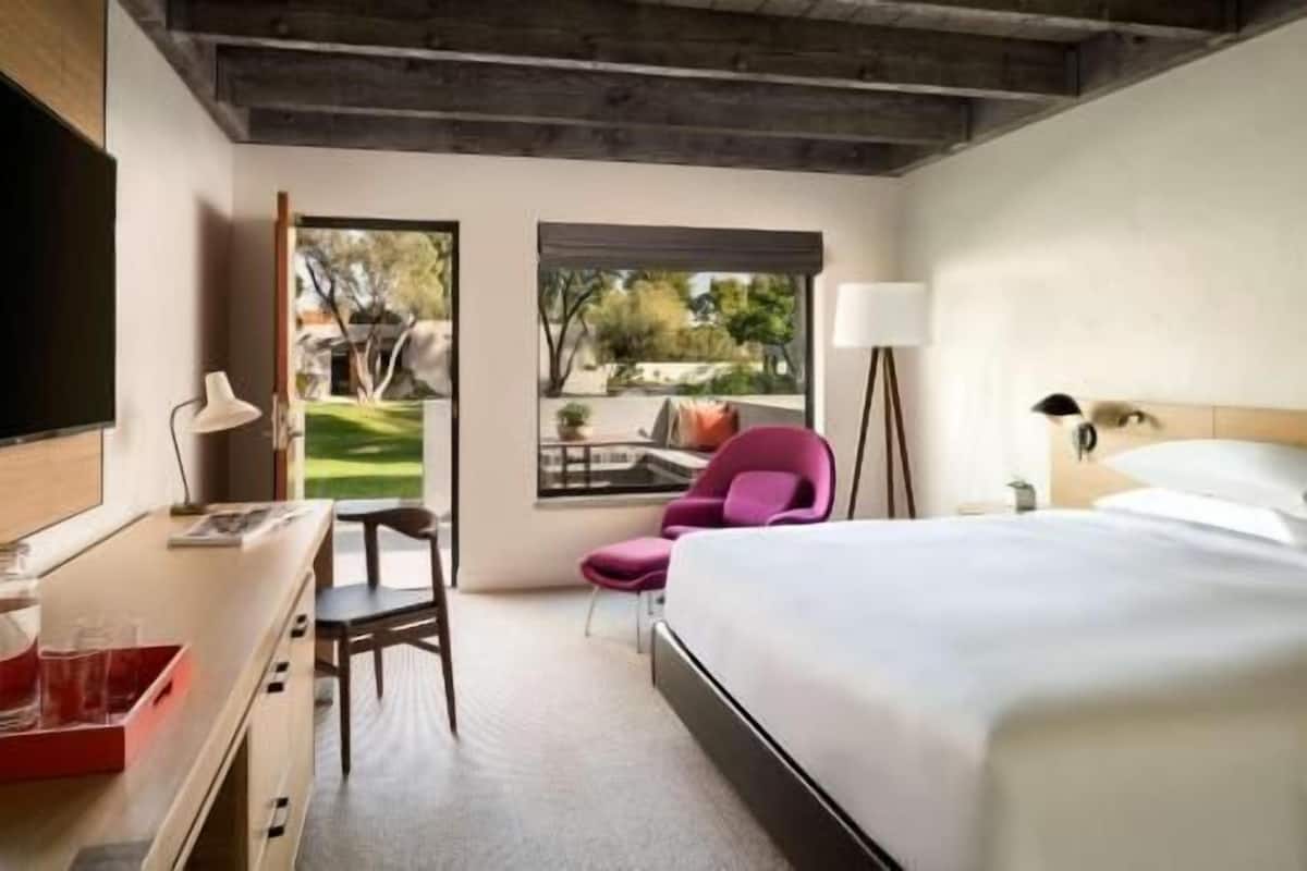 Une chambre d’hôtel équipée d’un lit, d’un bureau, d’une chaise et de deux fenêtres donnant sur l’extérieur.