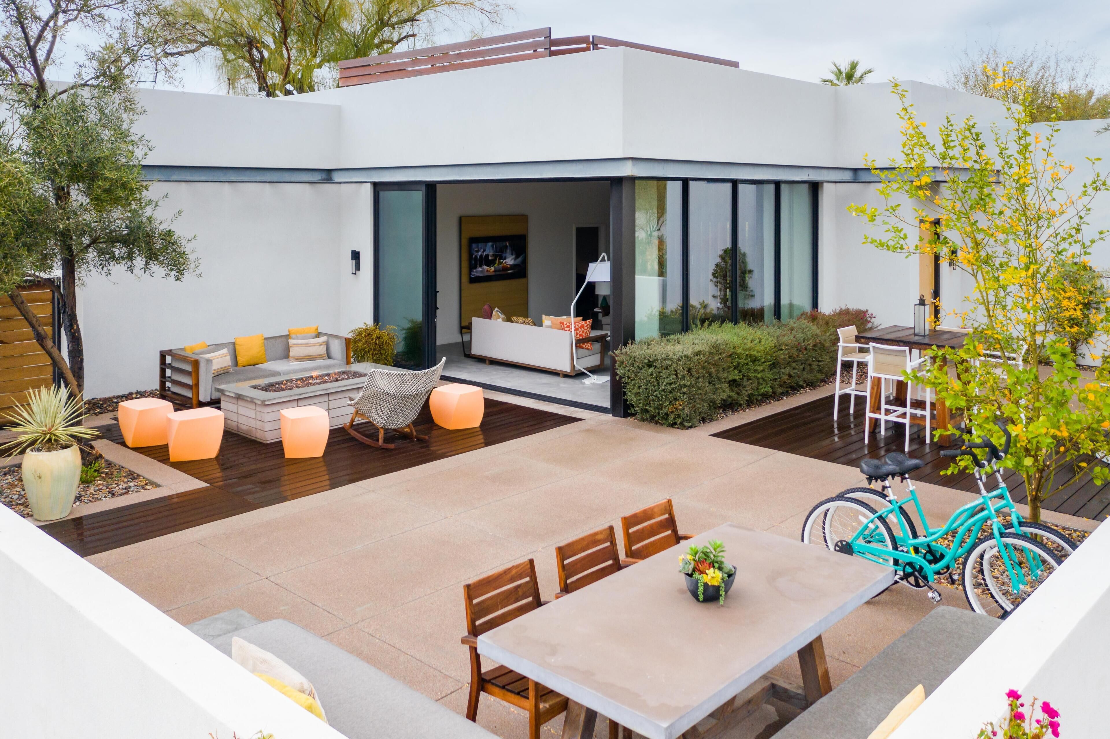 A modern outdoor patio with a dining table, chairs, and a bicycle.