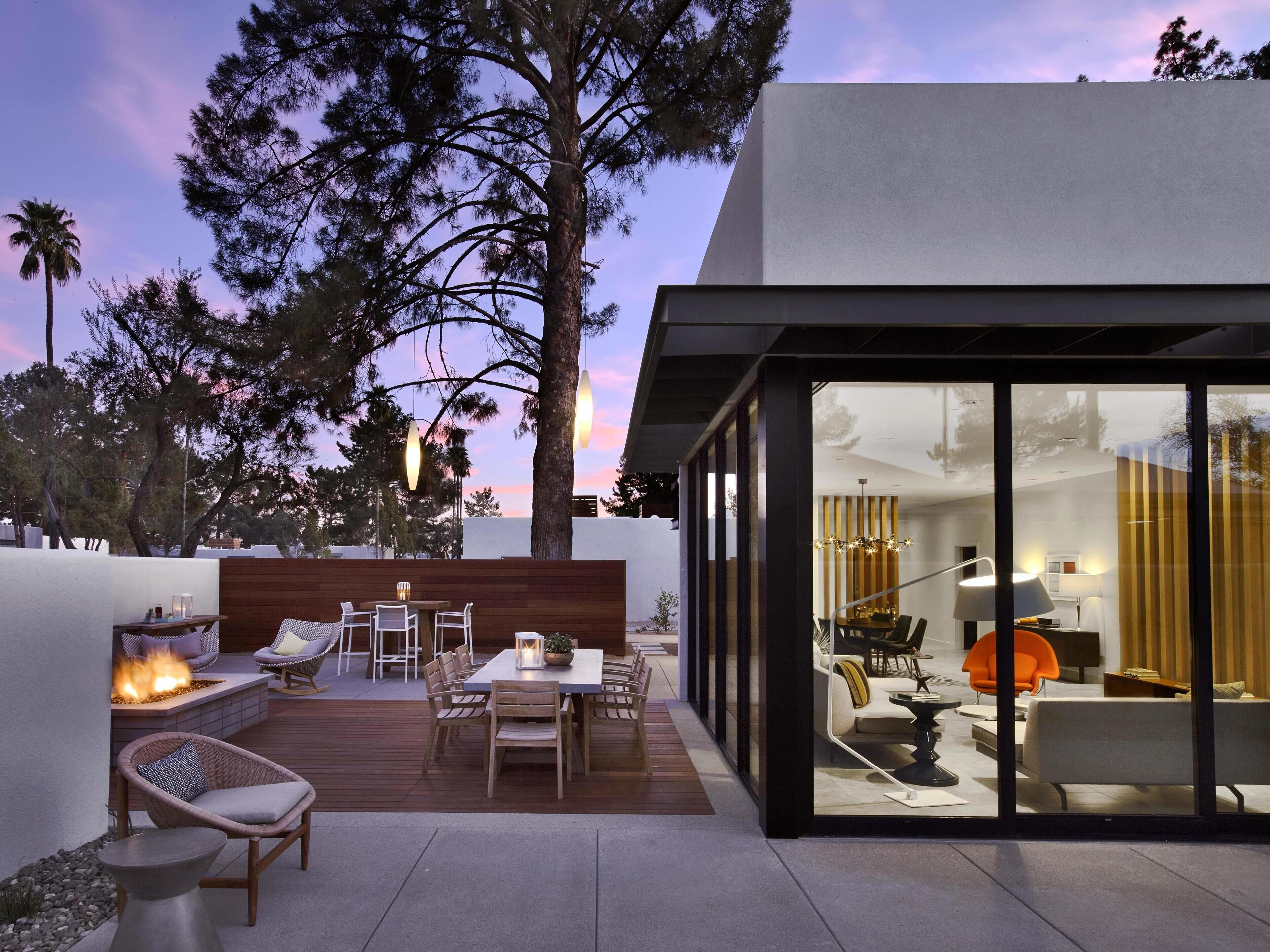Un patio moderno al aire libre con una chimenea, terraza de madera y zona de estar.