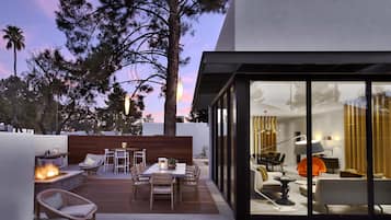 Un patio moderno al aire libre con una chimenea, terraza de madera y zona de estar.