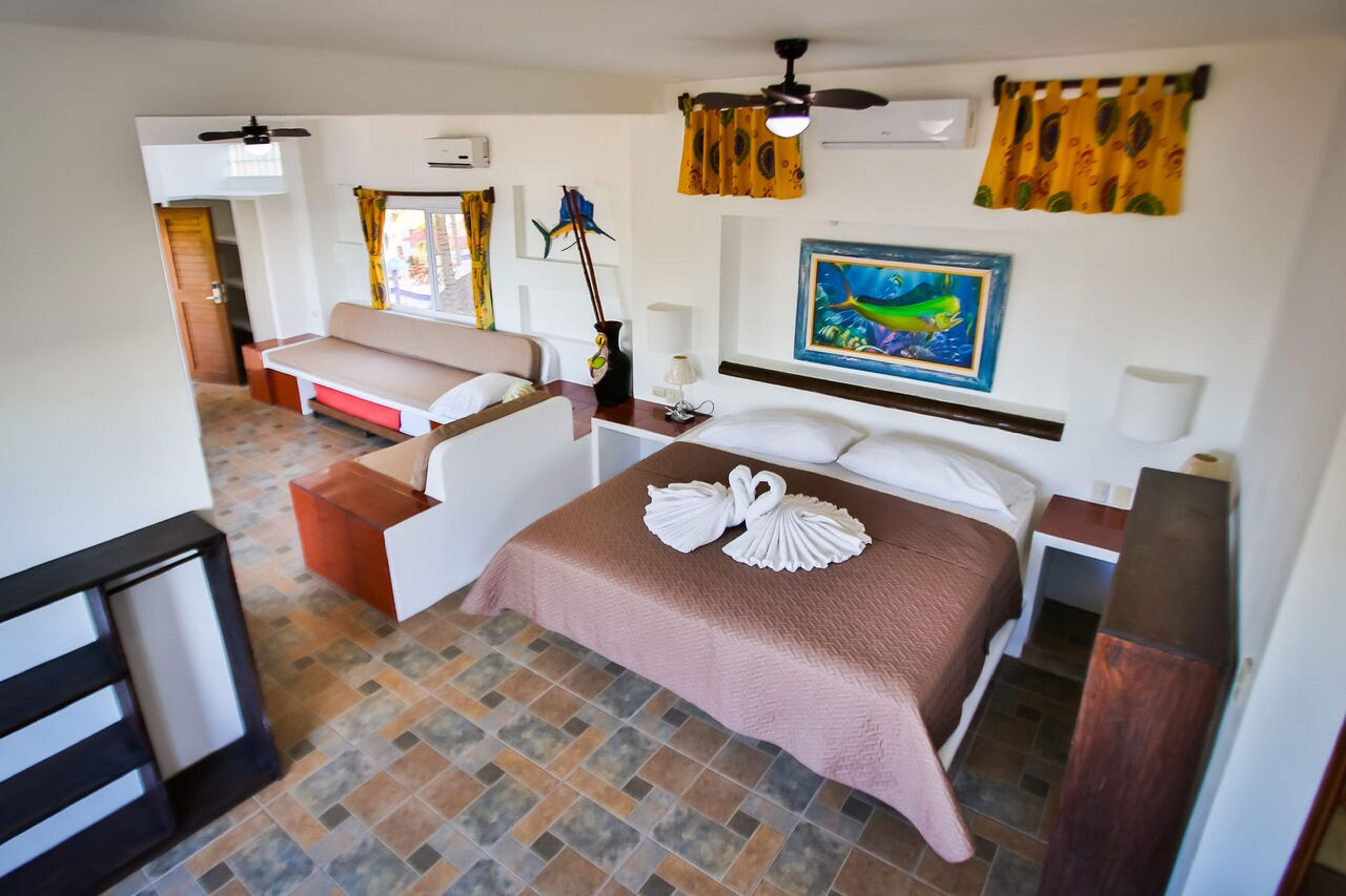 Una habitación de hotel con cama, sofá, escritorio y ventilador de techo.