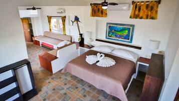 Una habitación de hotel con cama, sofá, escritorio y ventilador de techo.