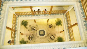 An indoor courtyard with a central fountain, surrounded by seating areas and a wooden balcony. - Hotel Presidente (Las Tablas)