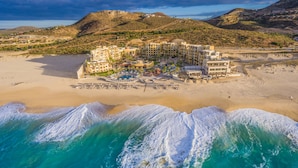 Ett flygbildsbild av ett hotell vid kusten med flera byggnader, en strand och ett poolområde.