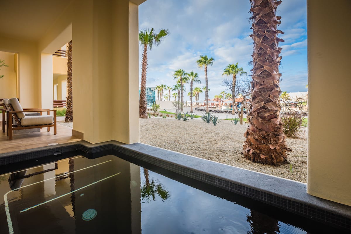 A pool area with a view of a sandy beach and palm trees.