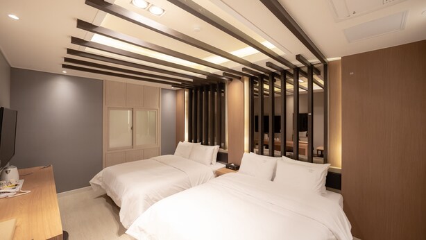 Habitación de hotel con dos camas, un escritorio y una televisión.