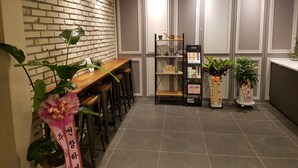 Una cocina moderna con pared de ladrillo, taburetes de madera, una estantería negra y plantas en macetas.