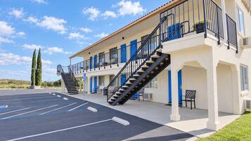 Un hotel con estacionamiento, varios balcones y una escalera que conduce a los pisos superiores.