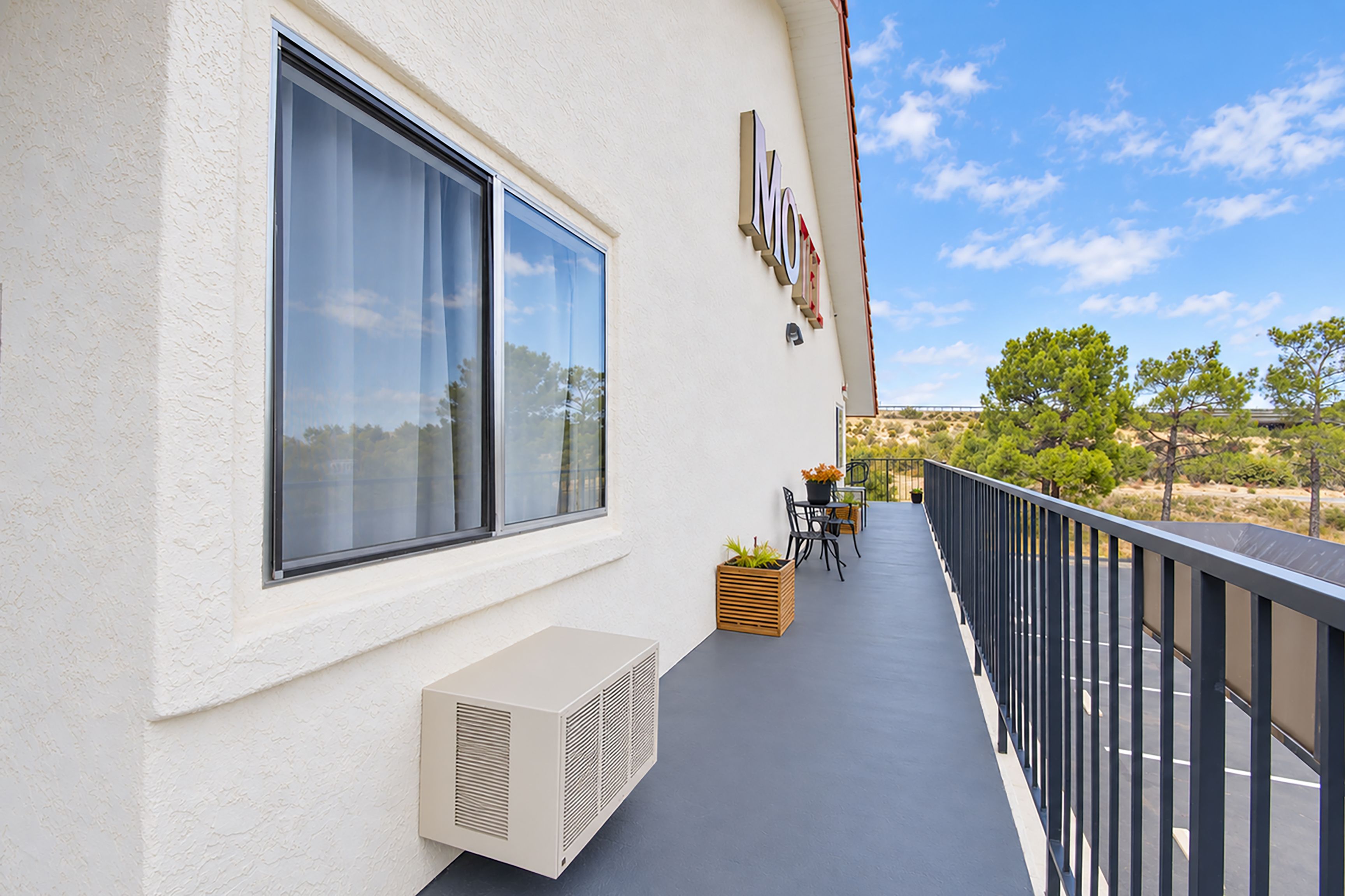 A balcony with a table and chairs, a potted plant, and a large window.