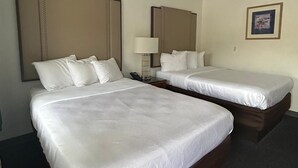 A hotel room with two beds, a desk, a lamp, and a ceiling light. - Backcountry Inn Motel (Boulevard)
