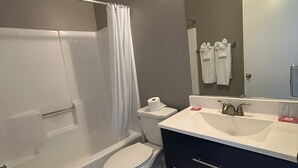 A modern bathroom with a bathtub, toilet, and vanity. - Backcountry Inn Motel (Boulevard)