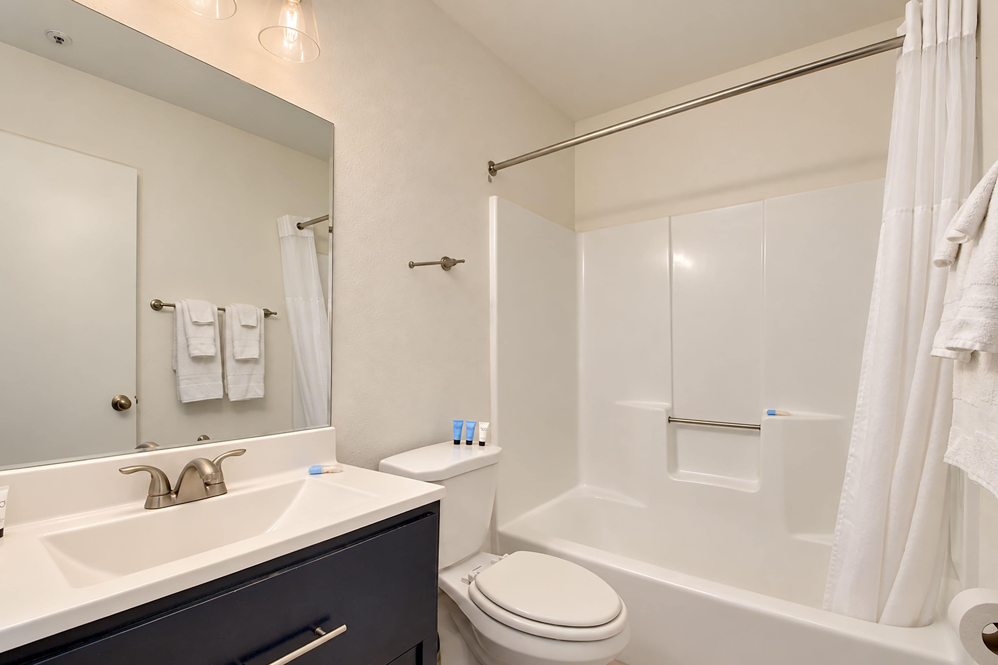 A modern bathroom with a vanity, toilet, and shower area.