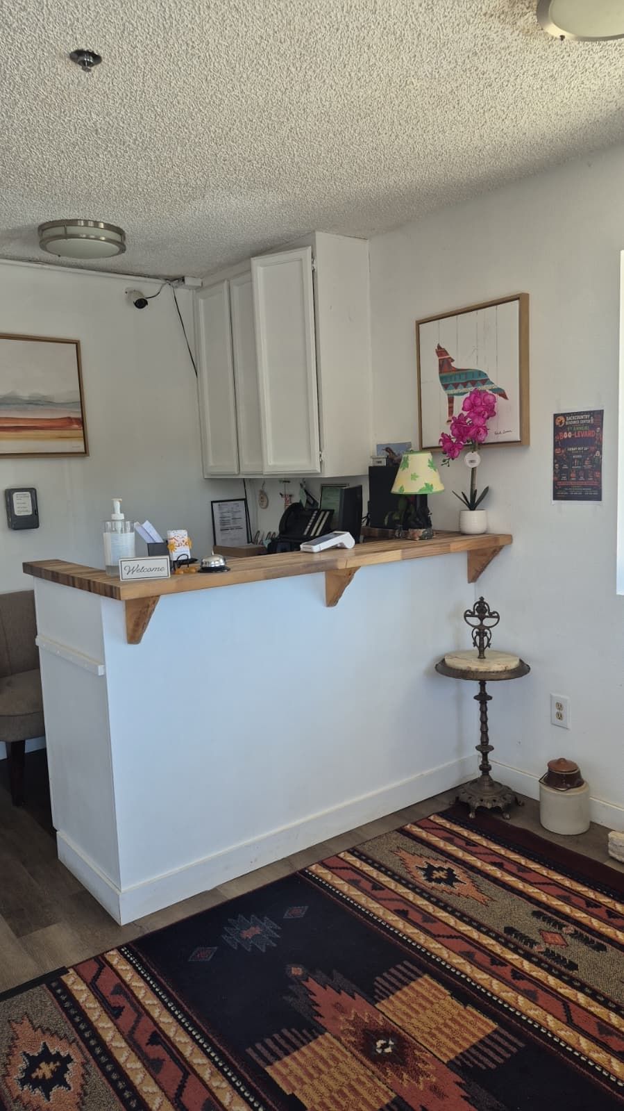 A compact kitchen with a wooden countertop, a small table, and a decorative lamp.