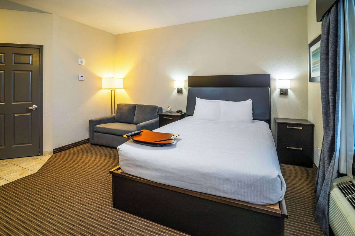 Une chambre d’hôtel avec un grand lit, un bureau, une chaise et une lampe.