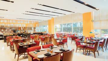 A spacious restaurant with multiple dining tables and chairs, large windows, and a bright interior.