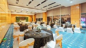 A banquet hall with round tables, white chairs with gold sashes, and a blue patterned carpet. - Fairfield By Marriott Lucknow (Lucknow)