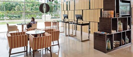 A modern reception area with a glass wall, a reception desk, and a seating area with wicker chairs.