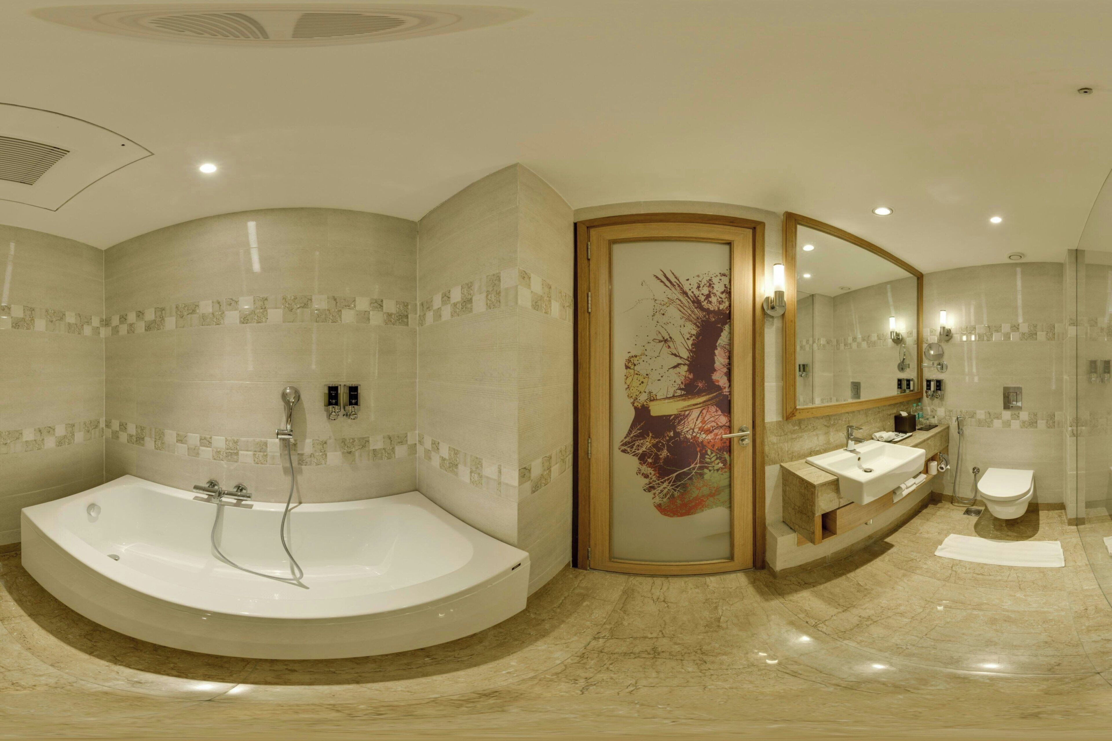 A modern bathroom with a large bathtub, a separate shower area, and a vanity with a sink and mirror.