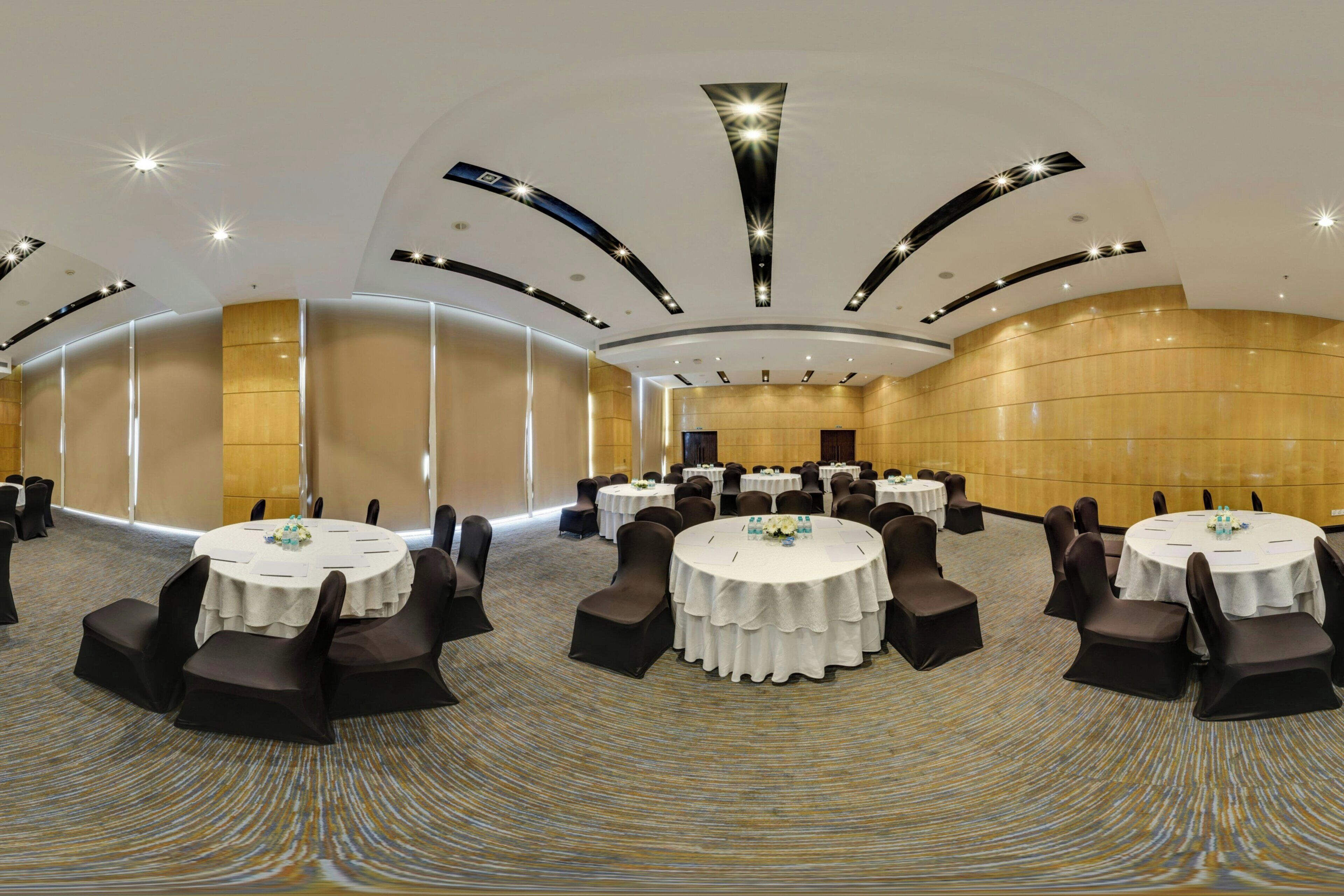 A conference room with round tables, black chairs, and a patterned carpet.