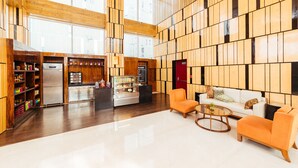 A spacious lobby with a modern kitchen area, a seating area with orange chairs, and a white sofa. - Fairfield By Marriott Lucknow (Lucknow)