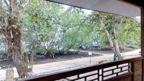 A view from a covered porch with a wooden railing, overlooking a dirt path and dense greenery. - Jonaths Cottage Bunaken (Pulau Bunaken)