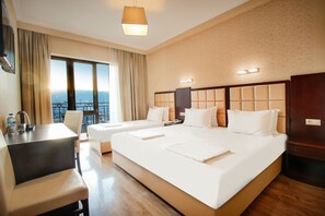 A hotel room with two beds, a desk, and a view of the city.