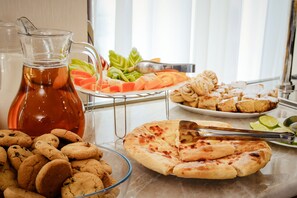 A table with food items including cookies, a pizza, and a pitcher of tea.