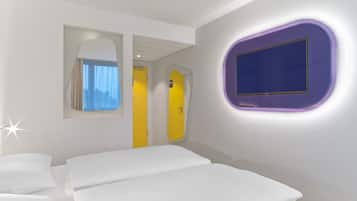A hotel room with a bed, a mirror, a door, and a wall-mounted TV.
