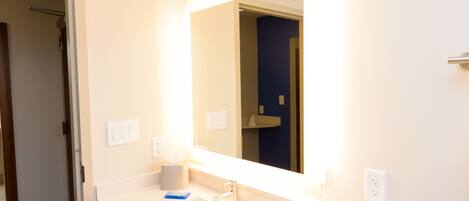 A bathroom with a white sink, a mirror, and a towel rack.