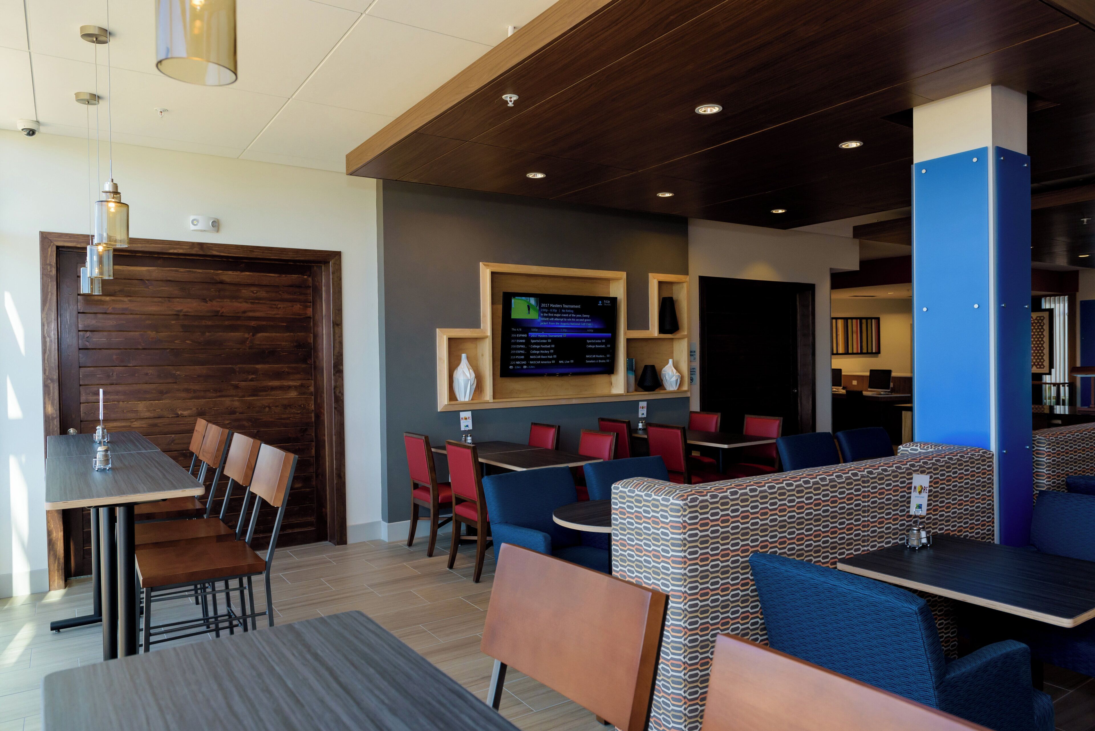 A restaurant with booths and tables, a TV screen displaying sports content, and a wooden ceiling.