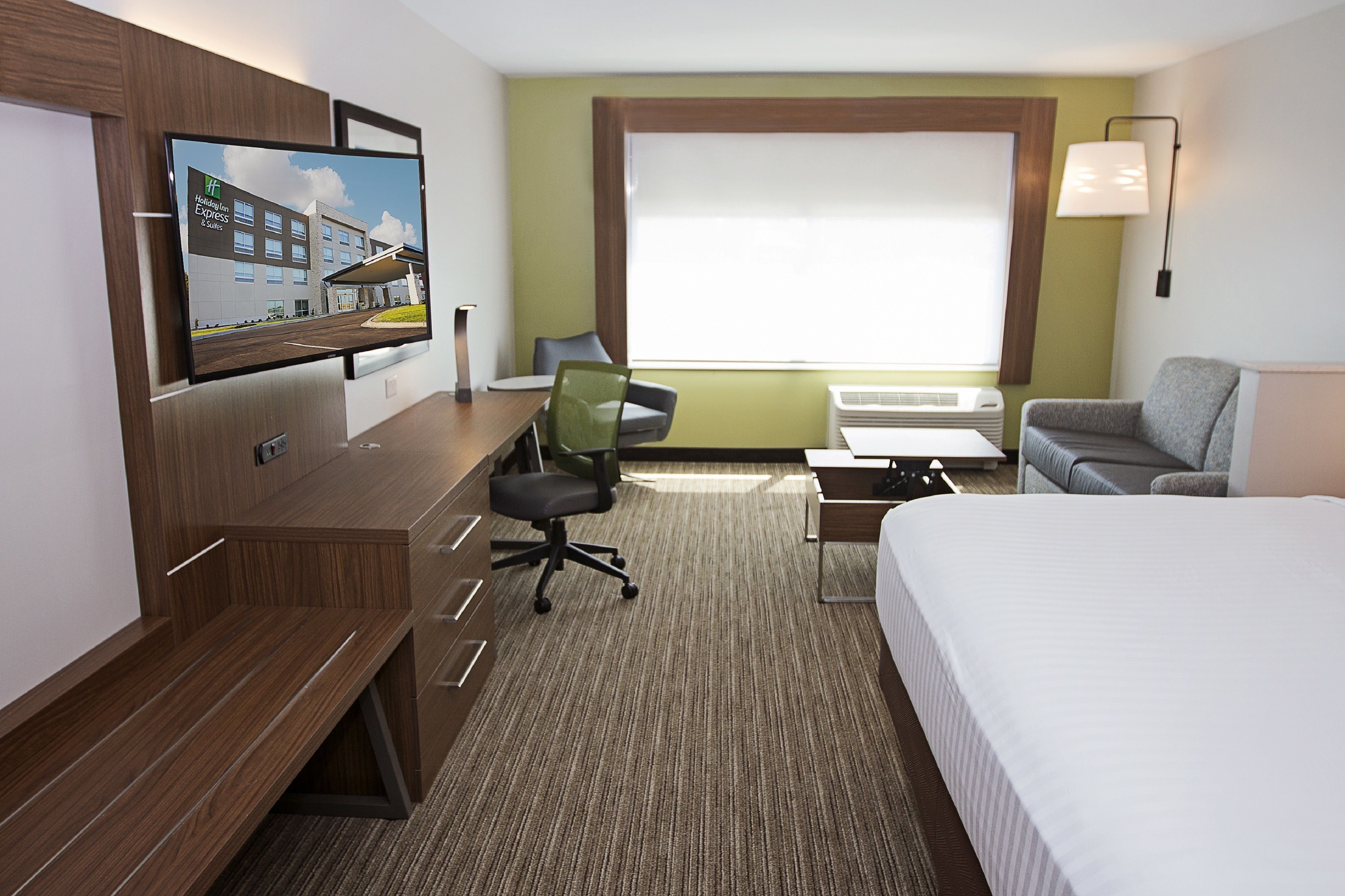A hotel room with a bed, desk, chair, TV, and window.